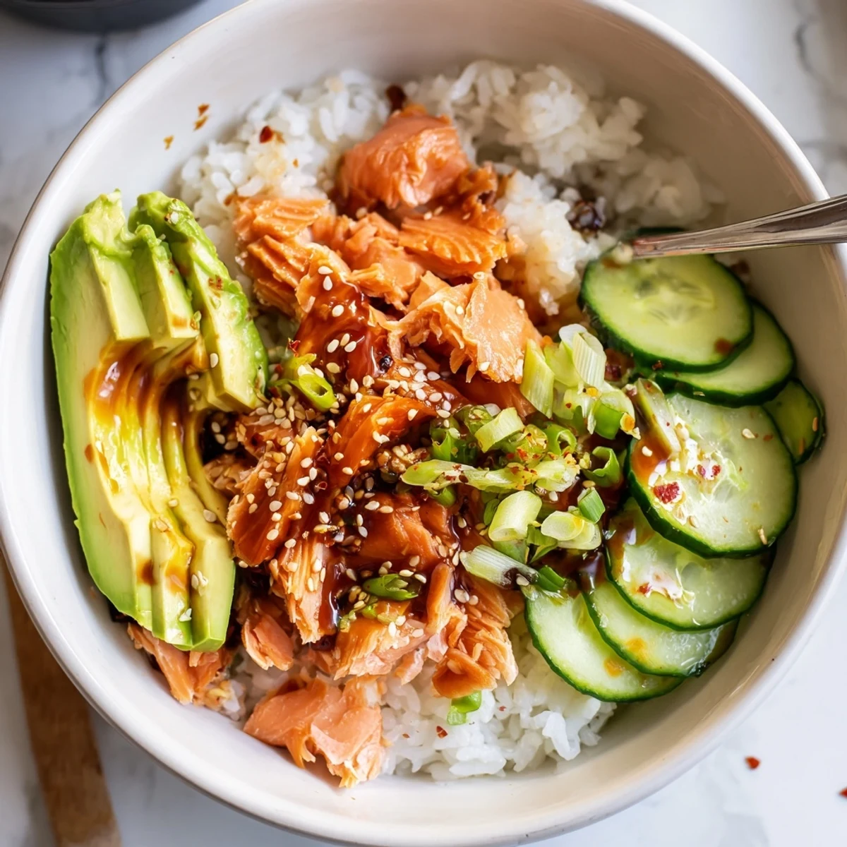 Vibrant leftover salmon and rice bowl with fresh avocado and cucumber toppings.  
