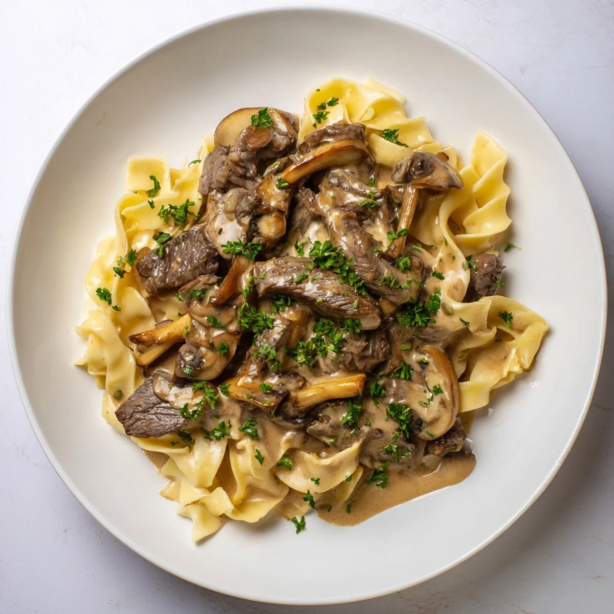 A steaming bowl of Creamy Mushroom Beef Stroganoff, served with fluffy egg noodles and fresh green parsley.