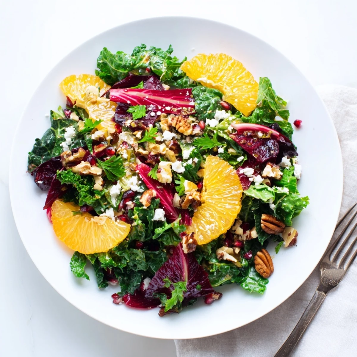A delicious bowl of Winter Greens Salad with ruby pomegranate seeds, perfect for a light vegetarian meal.