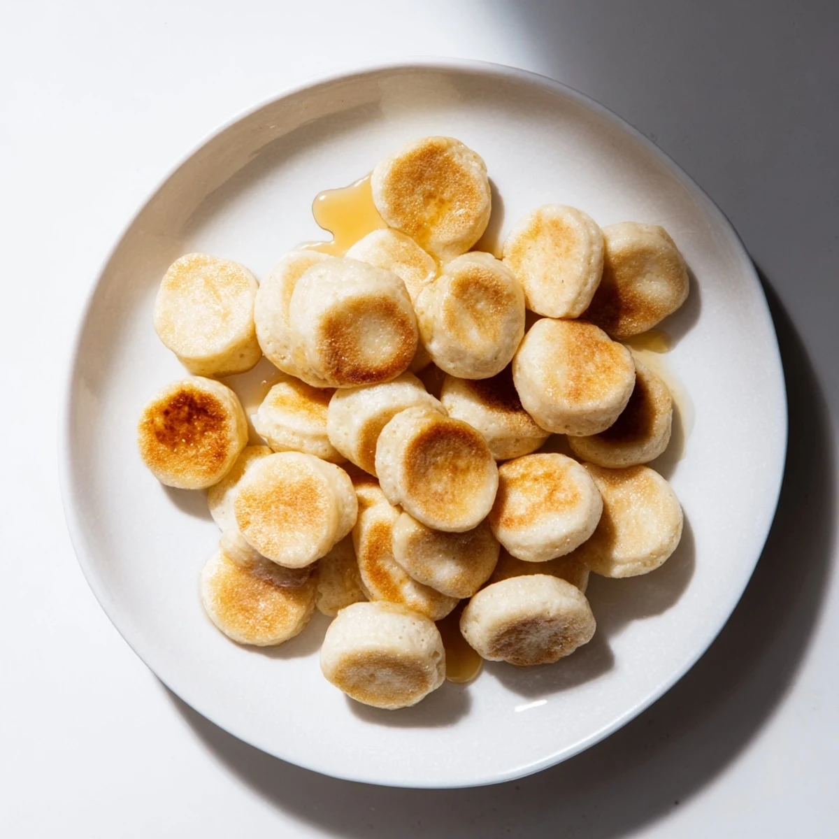 Mini pancake cereal, tiny golden pancakes piled high, ready to be drizzled with maple syrup.