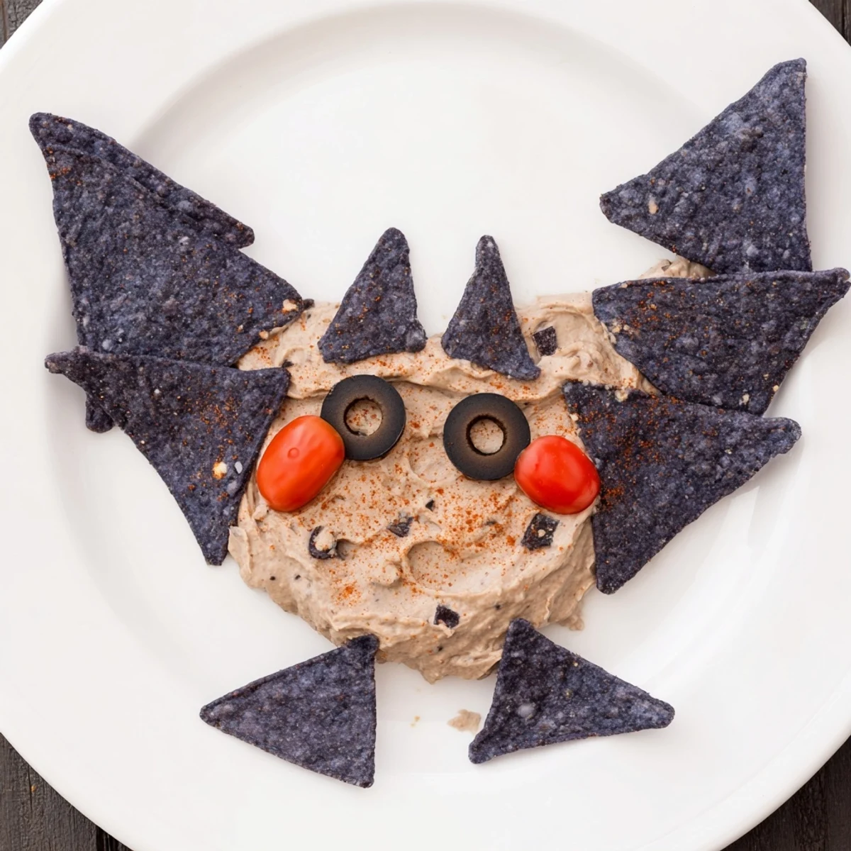 Creamy Spooky Bat Bean Dip Platter, artfully shaped with olive eyes and colorful veggies, ready to devour.