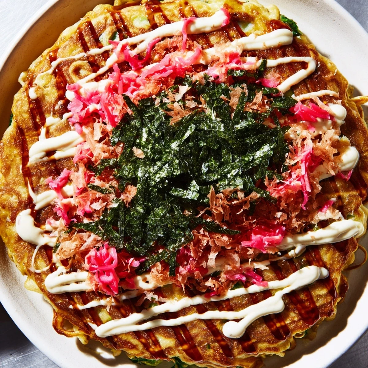 Golden, savory Japanese Okonomiyaki Pancakes piled with cabbage and shrimp, finished with aonori seaweed flakes.