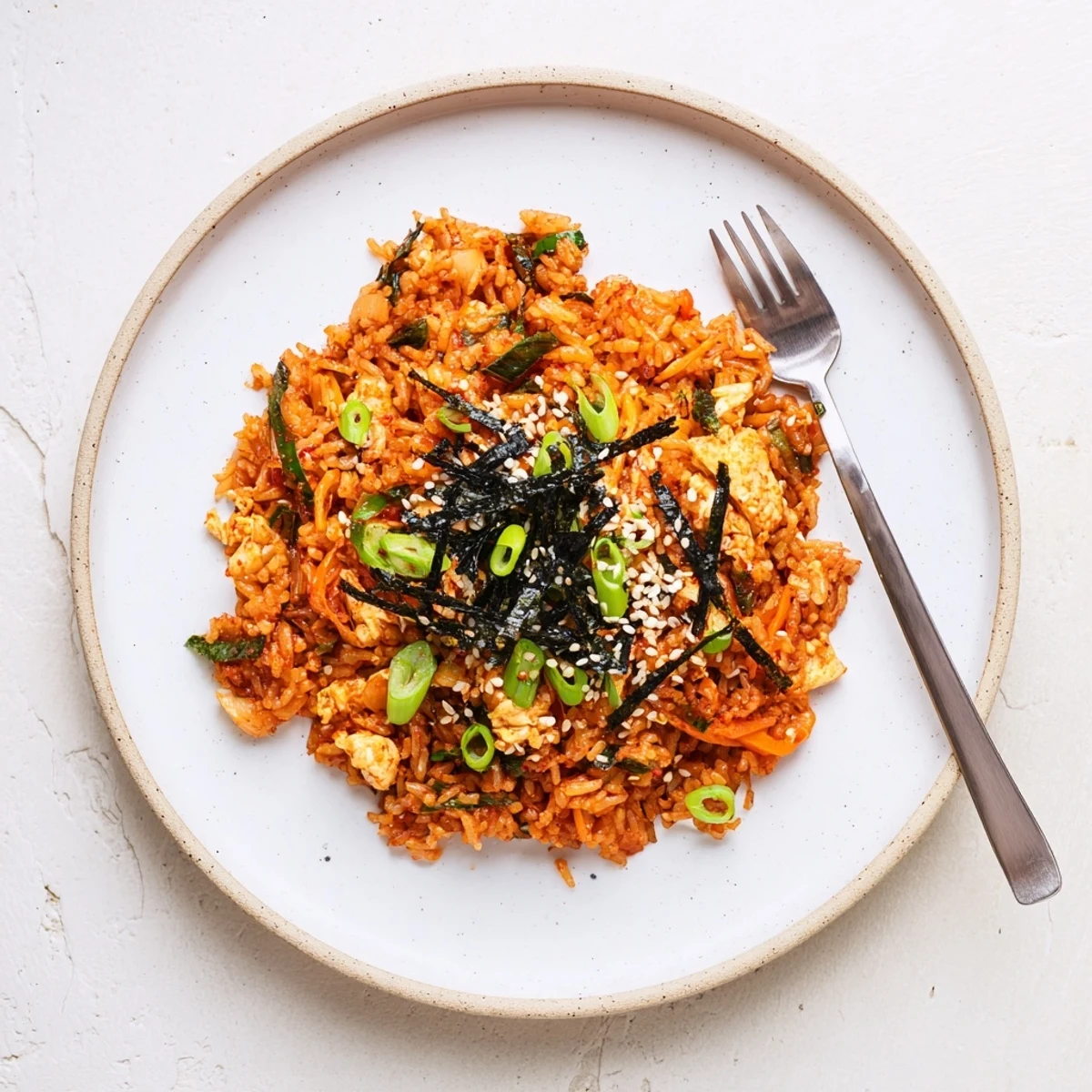 A steaming skillet of Spicy Kimchi Fried Rice with glossy grains, scrambled eggs, and fresh green onion garnish.  