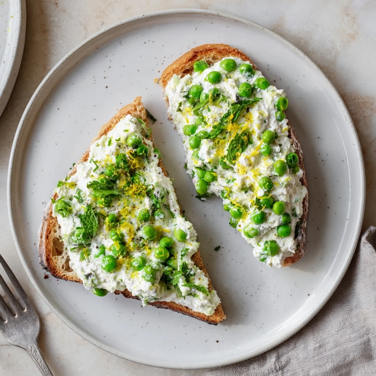Creamy pea and mint ricotta toast on toasted sourdough, brightened with lemon zest for a fresh, vibrant bite.  