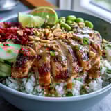 Bright julienned carrots and purple cabbage add color to a nourishing Coconut Rice Peanut Bowl garnished with chopped peanuts and lime.