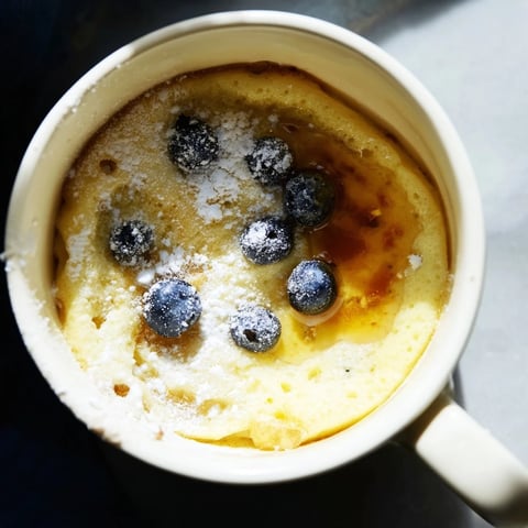 Steaming Microwave Mug Pancakes topped with golden syrup and fresh berries for breakfast.