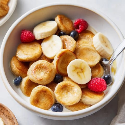Bite-sized pancake cereal in a bowl, perfect for breakfast with milk.  