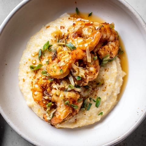 Golden, garlic butter coats plump shrimp atop creamy grits in this Shrimp & Grits portrayal.