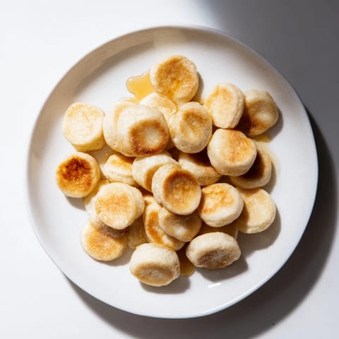 Mini pancake cereal, tiny golden pancakes piled high, ready to be drizzled with maple syrup.