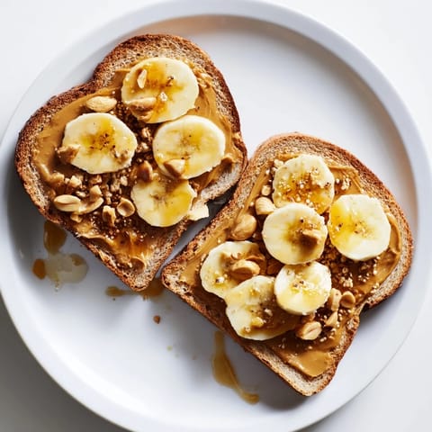 Crunchy peanut butter and banana sandwich with chopped peanuts and granola, a tasty treat.