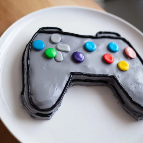 Imagine a fun Pixel Perfect Video Game Controller cake: frosted in gray with colorful button details, delicious flavors.