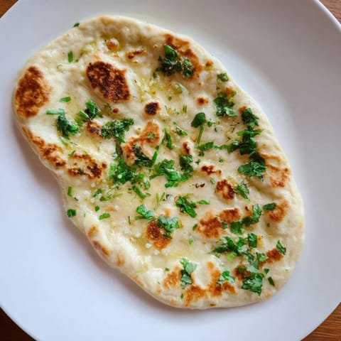 Golden-brown Homemade Garlic Naan Bread, hot off the pan, brushed with fragrant garlic butter.