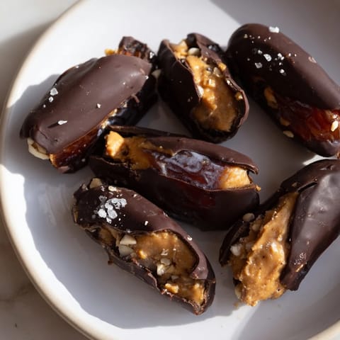 Dark chocolate-covered Chocolate Date Snickers with a peanut butter filling and salty sea salt sprinkle.