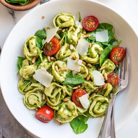 Fresh baby spinach adds a crisp green layer to the chilled Pesto Tortellini Salad, perfect for summer picnics or potlucks.