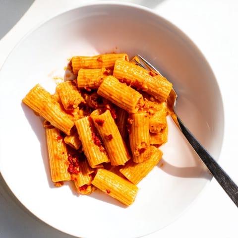 Steaming bowls of spicy rigatoni pasta with tender noodles, velvety sauce, and a sprinkle of Parmesan cheese, perfect for an easy weeknight meal.