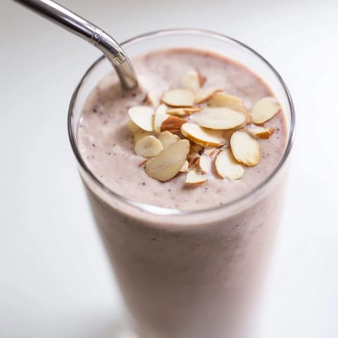 Two glasses of frosty Cherry Almond Smoothie garnished with extra cherries, ready for an easy, gluten-free, dairy-free snack.