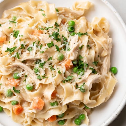 In a rustic skillet, sautéed onions and carrots mingle with peas and Parmesan, creating a comforting, family-friendly Spring Chicken Noodle Skillet ready in 35 minutes.