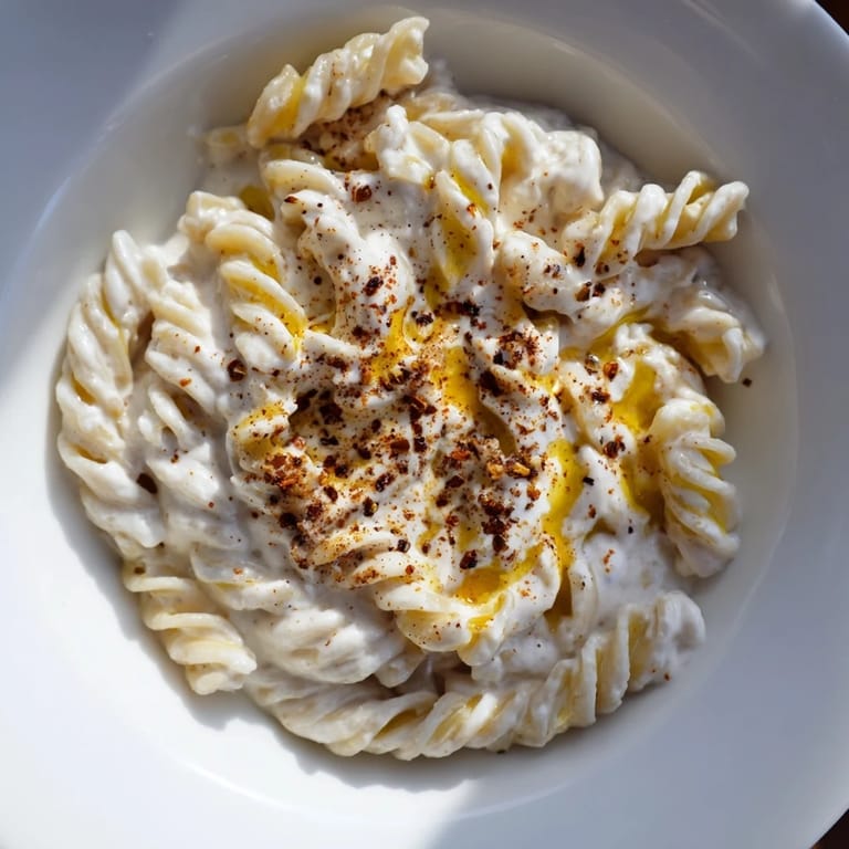 This close-up shows Turkish Yogurt Pasta, with tender noodles coated in a vibrant, spiced butter sauce.