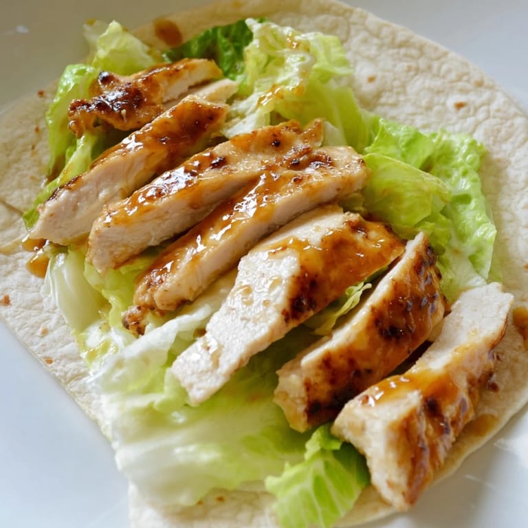 Fresh honey mustard chicken wrap ingredients ready for assembly, featuring chicken tenders, shredded lettuce, and red onion slices.